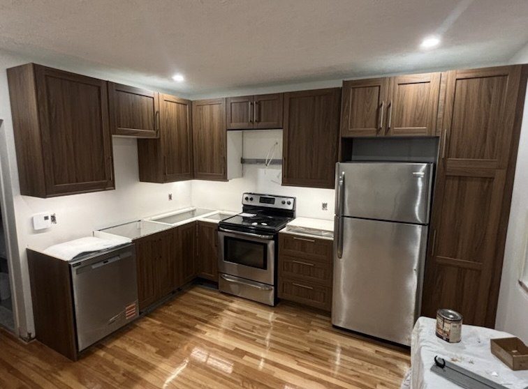 Newly renovated kitchen with dark wood cabinets and stainless appliances by Reno Island, Montreal